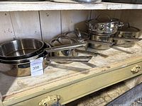 Shelved view showing multiple stainless steel pots and pans with lids.