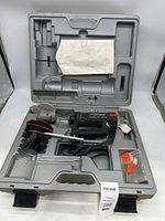 Rotozip Rebel cutting tool placed inside molded plastic case showing tool, power cord, sanding disc attachment, and some accessories including a plastic bag of small parts.