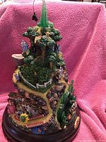 Front angle showing green Emerald City top, trees, multiple figurines, and yellow brick road on multi-level mountain base.