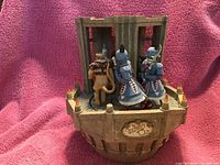 Photo shows music box with detailed figurines of Winkie guards and lion in front of gated castle tower base with Wizard of Oz plaque.