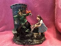 Photo showing a detailed figurine with Dorothy, the Scarecrow, and a melting figure near a stone tower backdrop.