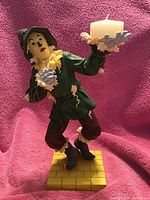 Full view of the Westland Wizard of Oz Scarecrow figurine holding a candle, standing on a yellow brick base.