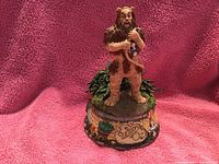 Cowardly Lion standing on a decorated music box base with Wizard of Oz theme.