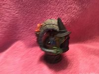 Image of a decorative collectible egg featuring a witch with a black hat and orange flower detail on a red fabric background.