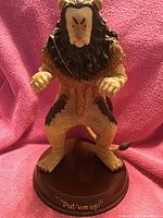 Front view of the 13-inch Cowardly Lion figurine from the Wizard of Oz, mounted on a base with inscription.