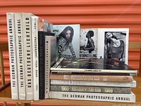 Photo of 14 photography books stacked up, showing titles and spines of photographic annuals and yearbooks from 1950s to 1970s.
