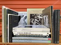 Side view of the 24 photography books and magazines showing spines with titles such as Photographers and Themes, Portraiture, and others.