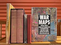 Six military history books standing upright showing spines and cover of 'War Maps'. Books include thick leather-bound volumes of 'The Ancient Art of Warfare' and other assorted books.