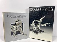 Photo showing two hardcover books side by side: 'Platinum by Cartier' with a panther sculpture image on cover and 'Oggetti Deco' featuring a silver-black sculpture of two stylized leaping animals.