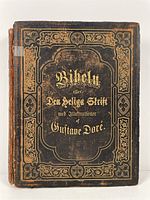 Closed front cover of vintage Gustave Doré illustrated Bible showing ornate gold embossed design on leather cover with visible wear and color fading.