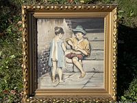 Front view of framed vintage painting featuring two children, one seated peeling an orange and one standing in a torn dress.