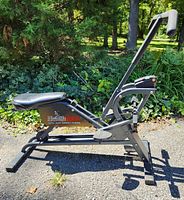 Side view of a black HealthRider exercise machine with padded seat and handlebars, set outdoors on pavement.