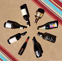 Photo of all 8 empty bottles laid out on carpet, showing various labels and a painted Grand Marnier bottle