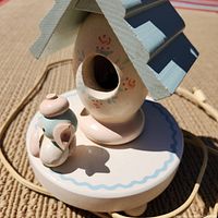 Close-up of birdhouse lamp base showing small bird figure and painted floral details