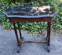Front view of vintage antique wooden table showing scalloped top, drawer front, and turned legs.