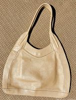 Front view of beige leather hobo handbag, showing smooth leather surface and classic shape.