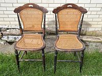 Both antique caned wood chairs shown side by side outdoors, front view.