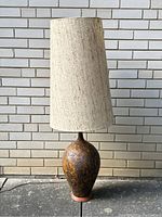 Full view of floor lamp against brick wall showing base and shade