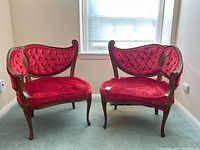 Front view of two red velvet tufted chairs positioned side by side in a room