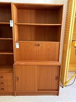 Full frontal view of the teak wall unit showing open shelves, drop-down desk closed, and bottom sliding doors