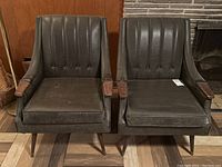 Front view of both chairs, showing vertical channel tufted backs, seat cushions, armrests and legs