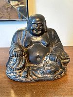 Front view of the vintage cast bronze laughing Buddha sculpture capturing its smiling face, detailed robes, and seated posture.