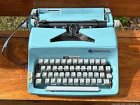 Front view of teal blue Commodore typewriter showing keys and logo