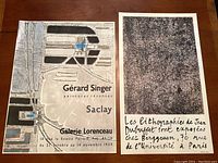 Pair of vintage French exhibition posters on wooden surface, showing full view of both posters side by side.