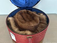Top-down view of red faux alligator embossed hat box open with mink shawl and hat inside