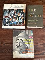 Three Picasso art books: 'Picasso' with colorful cubist painting on cover, 'Life with Picasso' book with dark cover and text, and 'The Private World of Pablo Picasso' paperback with black and white photo of Picasso wearing mask and hat.