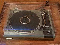 Front view showing the wood grain base and clear plastic dust cover over the platter and controls with Pioneer badge visible on front.