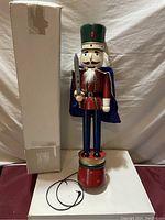 Full view of the 26-inch wooden nutcracker with box and cord