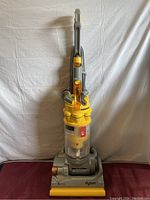 Frontal view of Dyson DC14 vacuum cleaner showing dustbin, base, and handle.