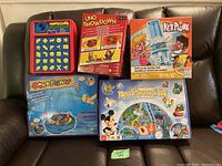 Five games displayed on a couch: Perfection, UNO Showdown, Kerplunk, Gone Fishin, Eye Found It.