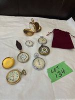 Group shot showing all seven items on white background: multiple pocket watches, one stopwatch, one watch head, one case cover, pouch