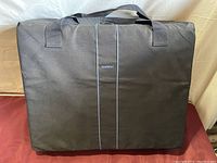 Black carrying case with BabyBjorn logo with shoulder straps, used for portable transport of crib items.