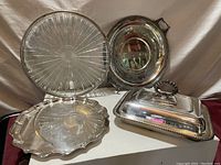 All four items displayed on table including rectangular covered dish, round platter, glass platter, and Birks plate.