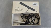 Original packaging box with AKAI ADM-60 microphone, cable coiled inside.