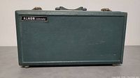 Closed view of ALNOR Velometer case, rectangular dark green with logo badge.
