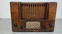 Front view of the vintage wooden Phonola tube radio with grille and control knobs