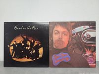 Front covers of two Paul McCartney LP albums: "Band on the Run" with a group photo, and "Red Rose Speedway" featuring Paul McCartney with a rose and a motorcycle.