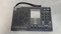 Front view of Sony ICF-SW7600 radio showing speaker, display, keypad and control buttons.