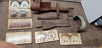 Photo showing two vintage stereoscopes, several stereoscopic cards with various historical images, and wooden and leather accessories.