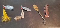 All four fishing lures displayed horizontally on a dark wooden surface