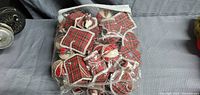 Bag containing multiple red fabric Christmas ornaments in various shapes with plaid and festive patterns