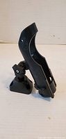 Black plastic kayak fishing pole holder on a flat surface showing front side with adjustable base and mounting holes.