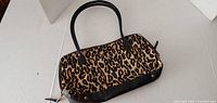 Front view of small hobo carry bag with leopard print and black leather base and handles.