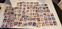 Image of front faces of about 40 baseball cards arranged in rows on white surface, each card inside clear plastic protector, showing players in various baseball poses and uniforms.