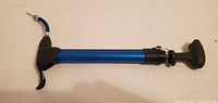 Front view of the blue travel bicycle pump showing the T-handle and hose attachment.
