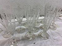 Two sets of antique crystal champagne flutes together, showing carved and geometric designs.